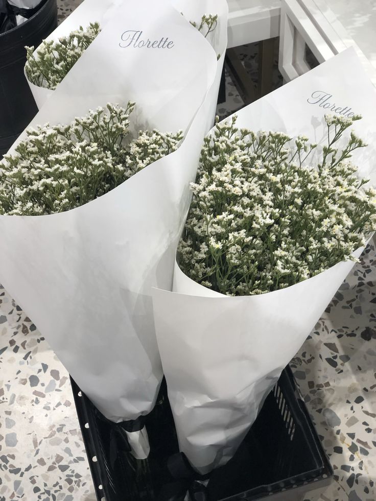 two bouquets of flowers are wrapped in white paper