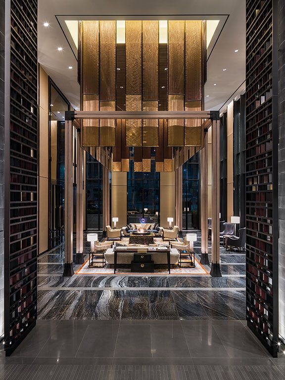 an elegant living room with wood paneling and marble flooring is lit by recessed lights