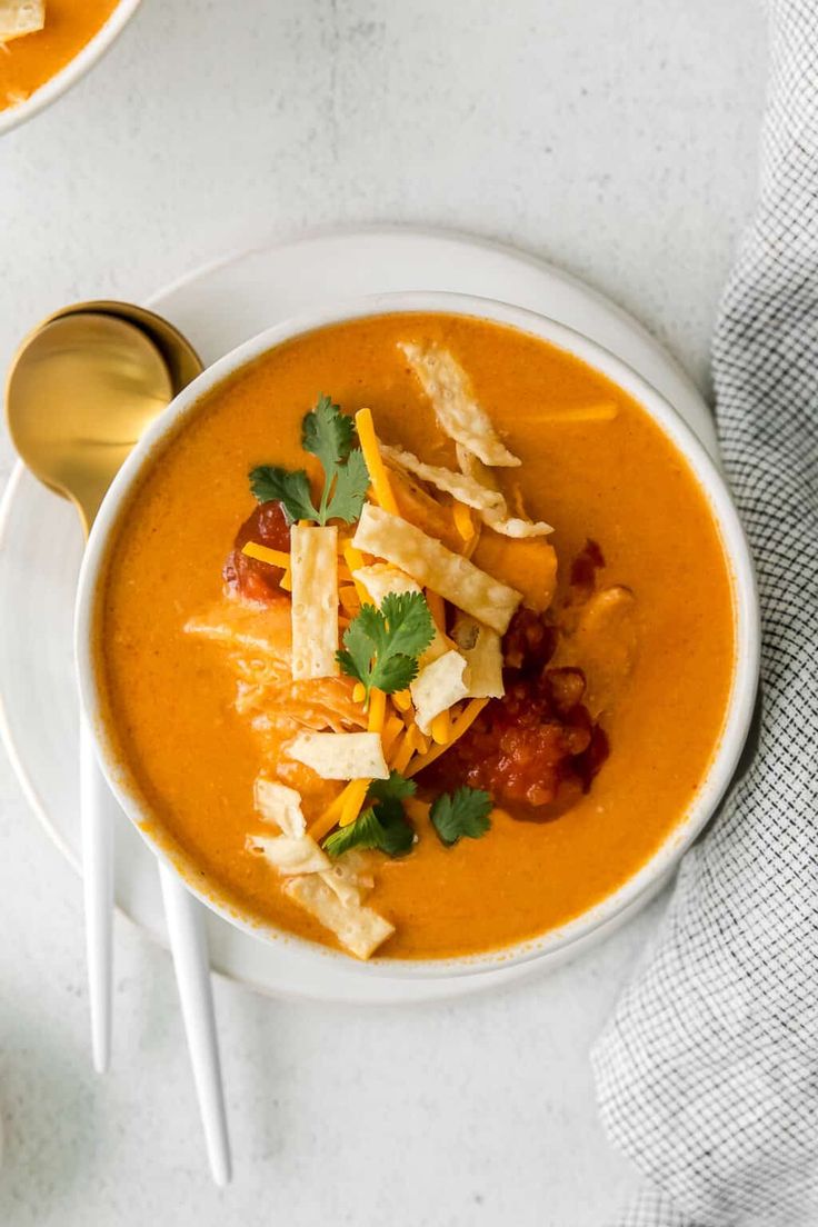 two bowls of soup with tortilla chips and garnish on the side