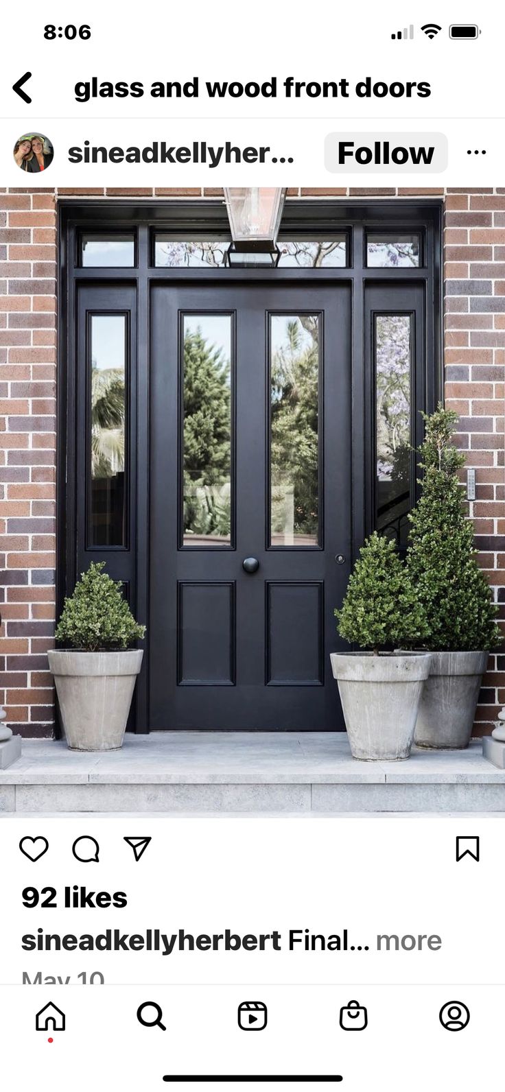 a black door with two potted plants on the side and an instagram page below