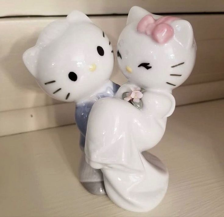 two hello kitty figurines sitting on top of a table