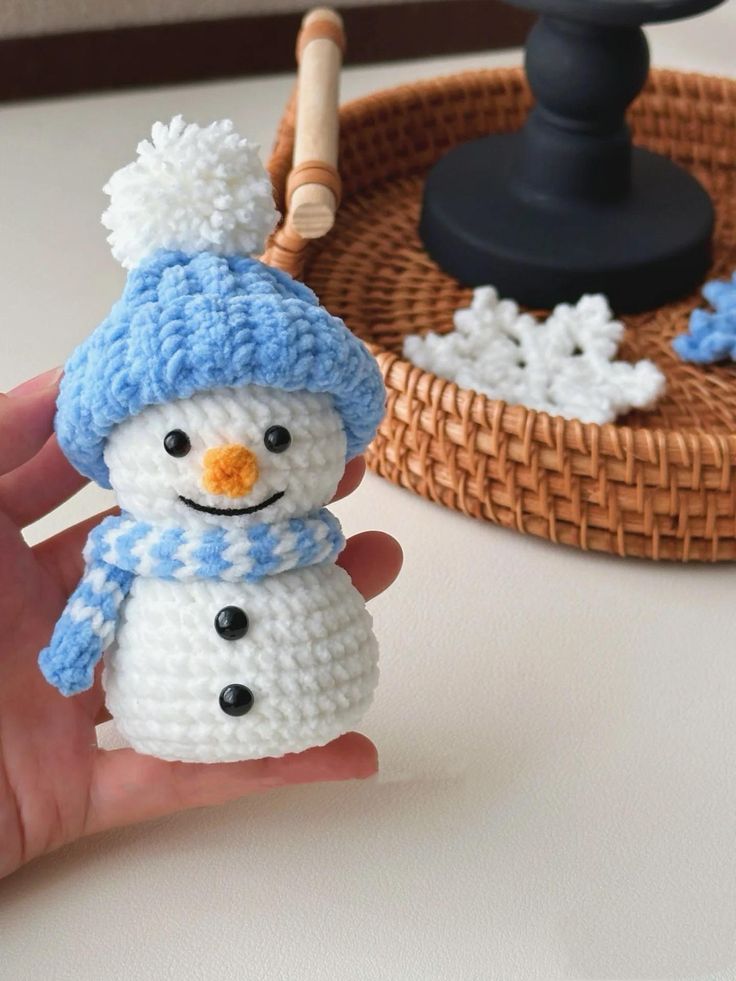 a hand is holding a small crocheted snowman