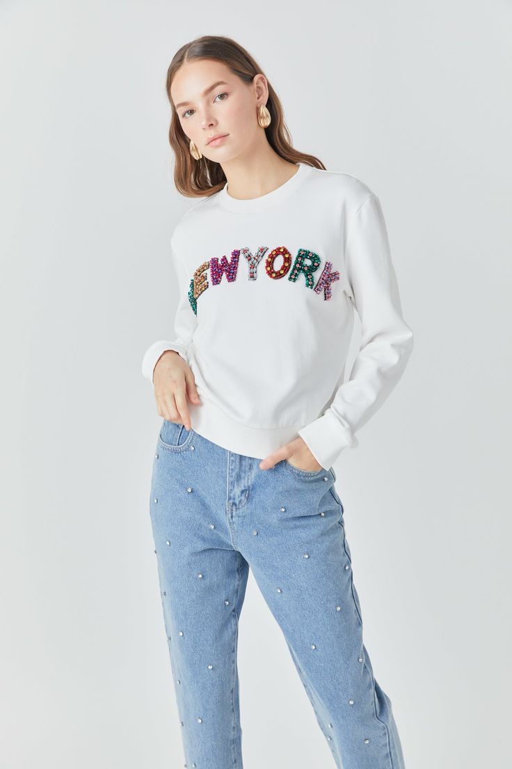 Add a touch of Big Apple flair to your wardrobe with our New York Embellished Sweatshirt. Made with soft, cozy material and a relaxed fit, this sweatshirt is perfect for all-day comfort. The round neckline and long sleeves add a classic touch, while the New York embellishment brings a stylish twist. Versatile enough to wear with anything, this sweatshirt is sure to become your new go-to. Upgrade your hoodie and sweatshirt collection with our must-have New York Embellished Sweatshirt. Sweatshirt Fall Sweater With Embroidered Text, White Tops With Embroidered Text For Fall, Trendy White Sweatshirt With Embroidered Text, White Trendy Sweatshirt With Embroidered Text, Sweatshirt Collection, Embellished Sweatshirts, Knit Bottom, Tweed Dress, Blazer And Shorts