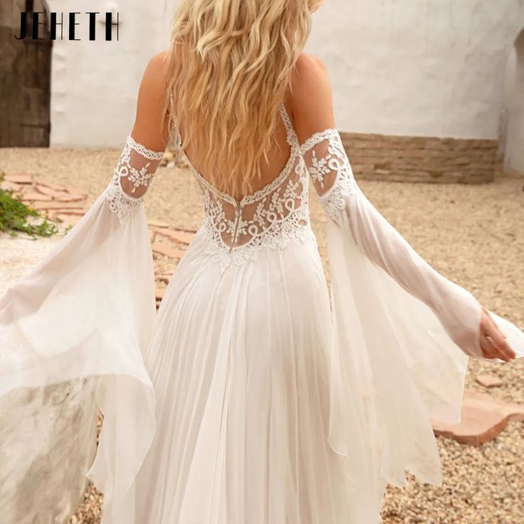 the back of a woman's white wedding dress with long sleeves and open shoulders