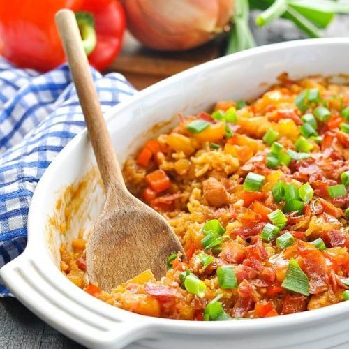 a white casserole dish filled with rice and vegetables