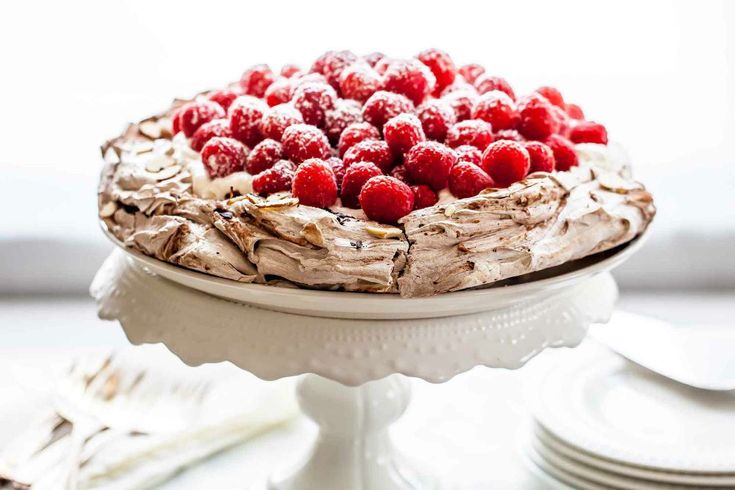 a cake with chocolate frosting and fresh raspberries on top is sitting on a plate