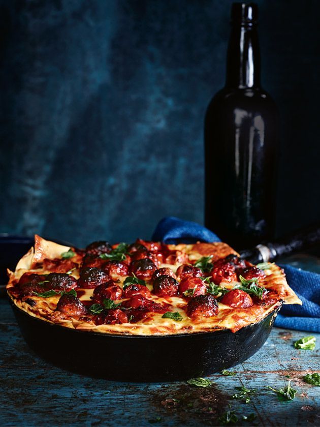 a pizza sitting on top of a pan covered in sauce and toppings next to a bottle