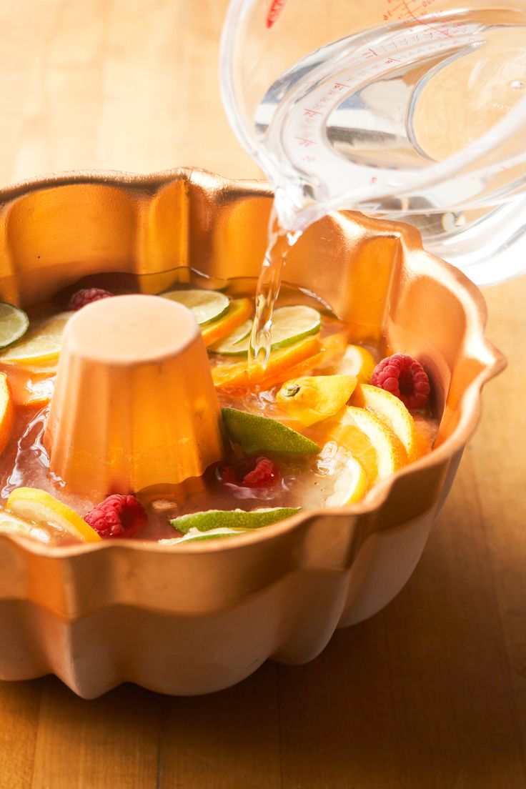 a bowl filled with fruit and water on top of a wooden table