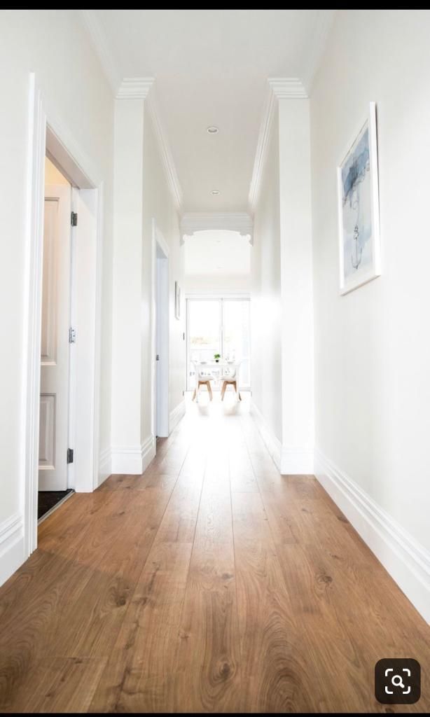 an empty hallway with wooden floors and white walls