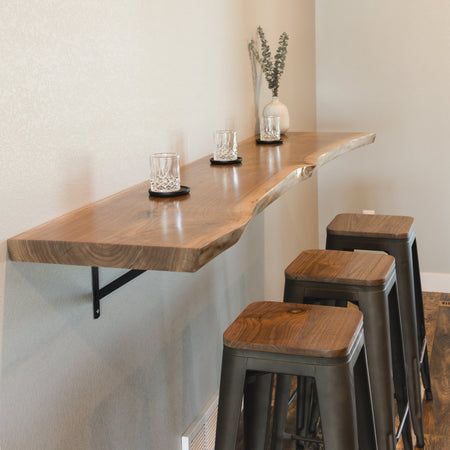 three bar stools sit at the end of a long counter with two cups on it