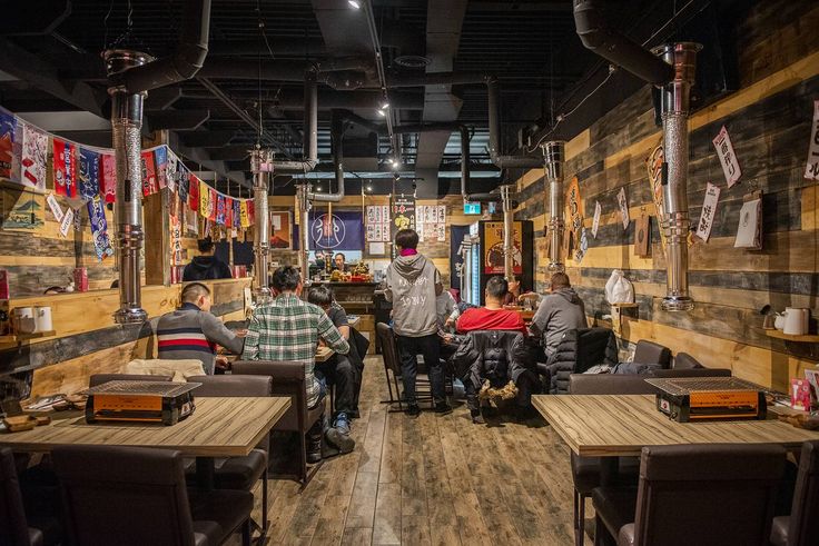 people sitting at tables in a restaurant with flags hanging on the walls and wood flooring