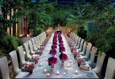 a long table is set with candles and flowers for an elegant dinner in the garden