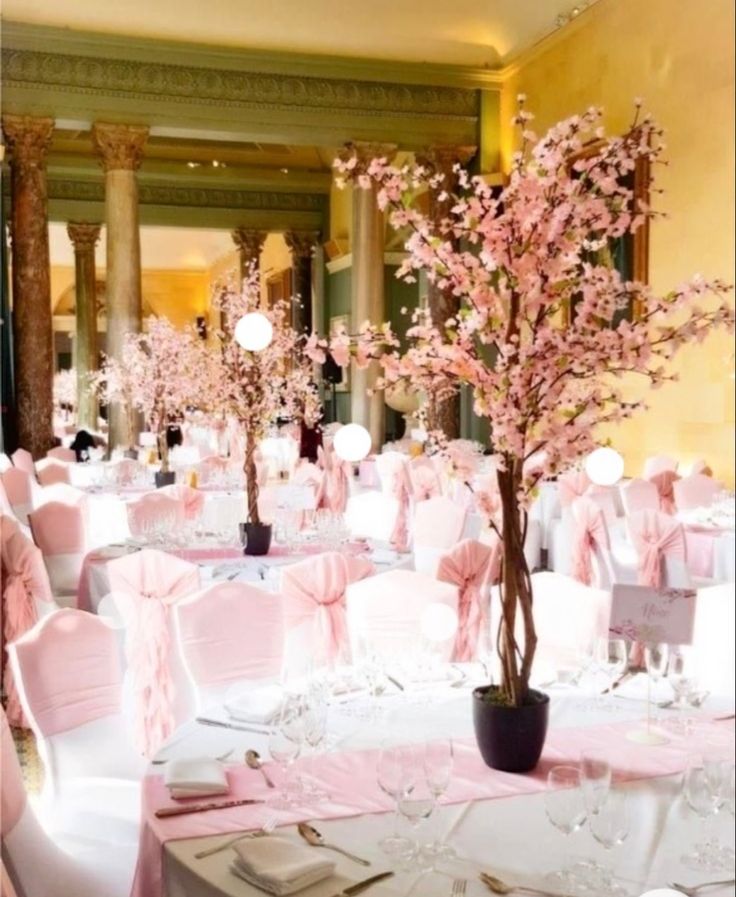 the tables are decorated with pink flowers and white linens for an elegant wedding reception