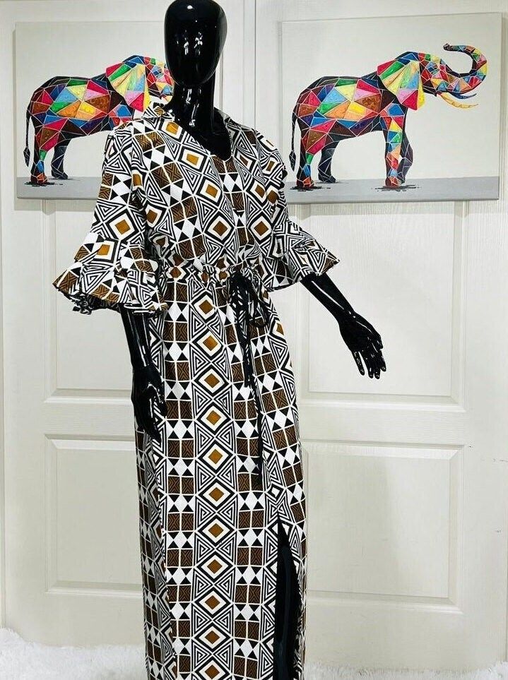 AKI African Tribal Print Dress Handmade with authentic 100% cotton Ankara. The AKI African Ankara Dress is casual and beautiful! It is the perfect dress for all your African celebrations and occasions. The bold, vibrant, geometric, and captivating colors in this dress will certainly make you memorable. AKI is suitable for parties, weddings, nights on the town, graduations, engagements, outdoorings, and so much more. Professionally hand-crafted and finished. FEATURES Maxi Length V Front Neck Shirt Colar Ruffle sleeves Draw String Tie At the Waist Front Slit FABRICATION 100% Cotton Non-Stretch CARE Hand Wash In Cool Water Use Mild Detergent Hang To Dry Do Not Machine Wash Do Not Bleach Steam Iron On the Reverse Side Black Cotton Tunic Dress, Black Cotton Maxi Dress For Vacation, Patterned Cotton Maxi Dress For Vacation, Brown Cotton Maxi Dress, Cotton Festival Dress With Kimono Sleeves, Bohemian Brown Cotton Dress, Brown Cotton Maxi Dress For Vacation, Fitted Cotton Bohemian Kaftan, Traditional Cotton Dress With Kimono Sleeves