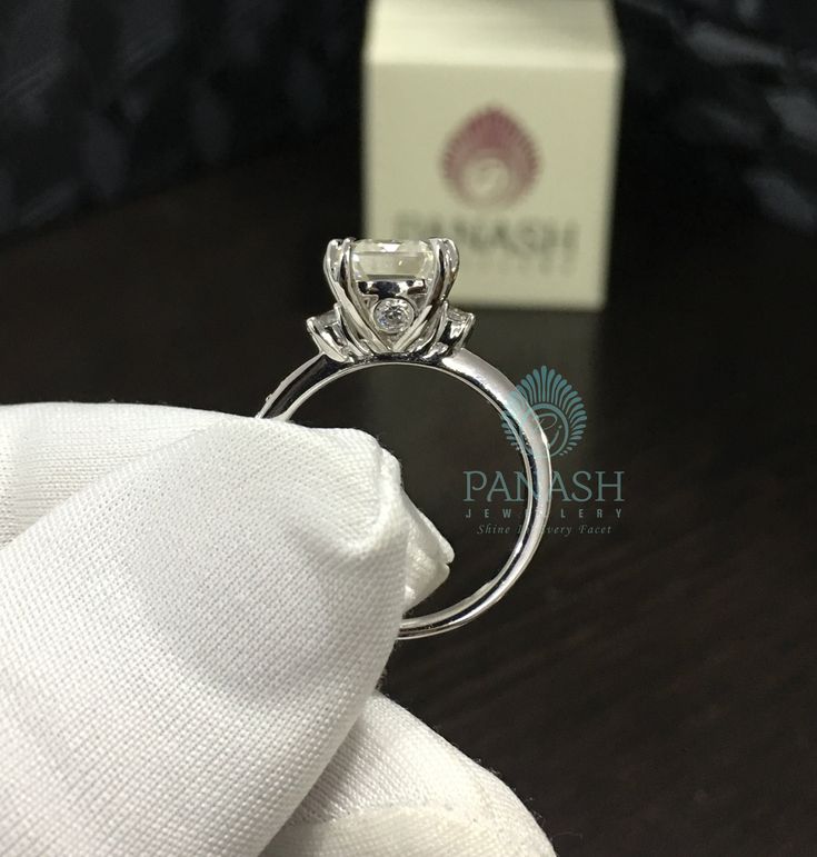 an engagement ring is sitting on top of a napkin in front of a box with a white cloth around it