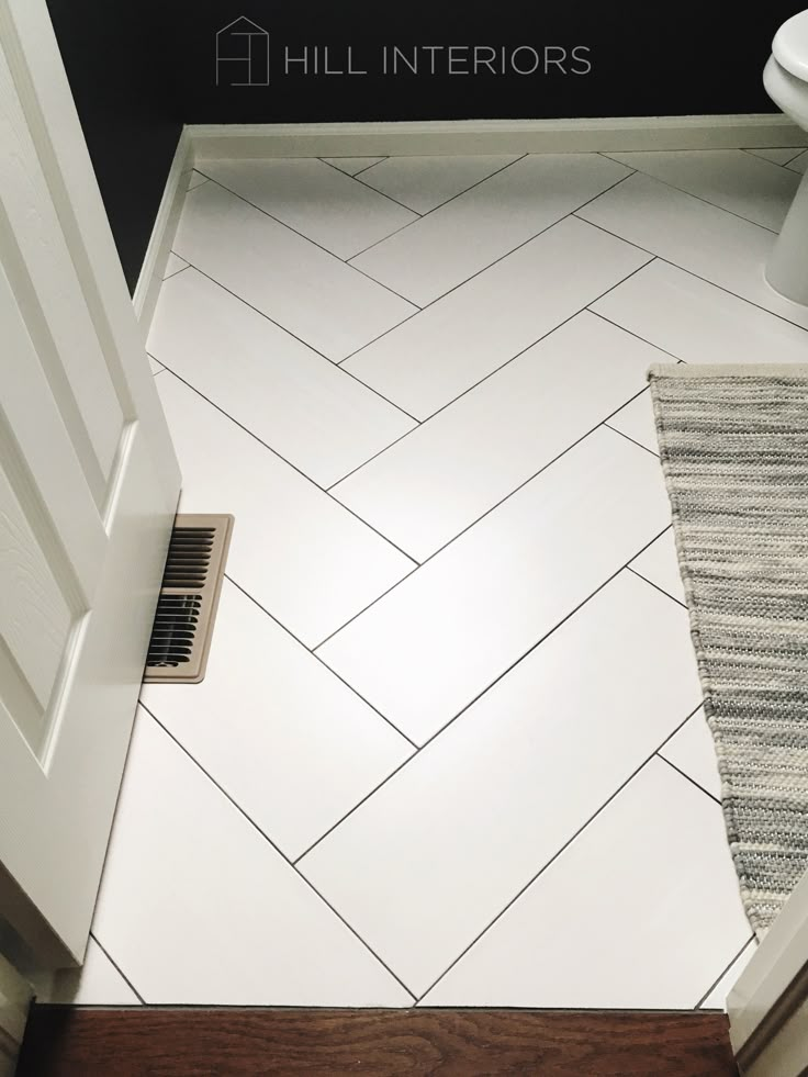 a bathroom with white tile and wood flooring next to a toilet in the corner