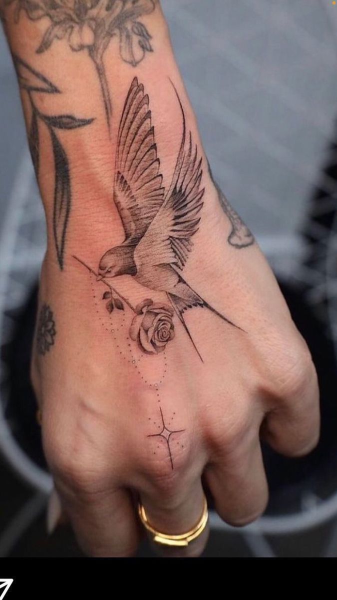 a person's hand with a bird and flower tattoo on it