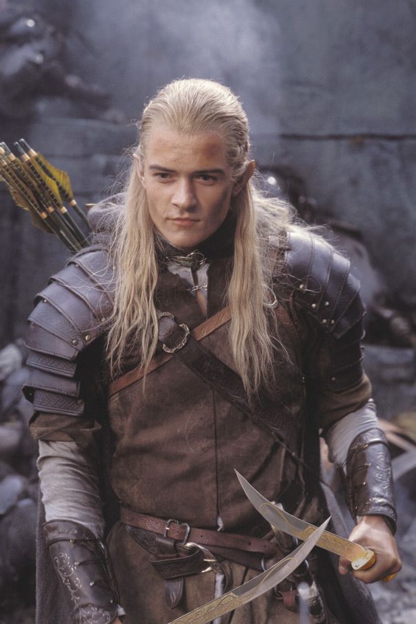 a man with long blonde hair holding two swords in his hand and looking at the camera