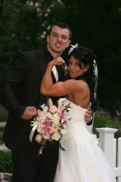 a bride and groom posing for a photo in front of a white fence with flowers