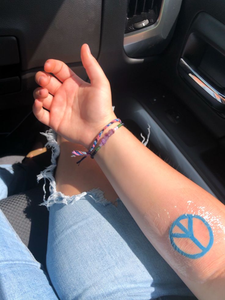 a person with a peace sign tattoo on their arm sitting in the drivers seat of a car