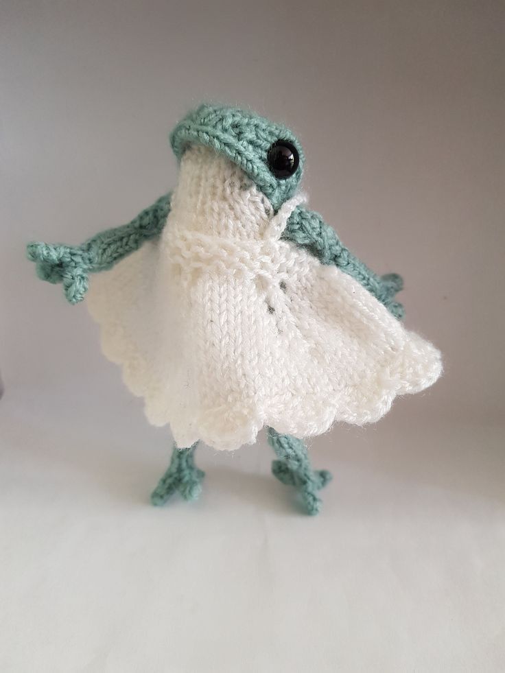 a crocheted frog is wearing a white dress