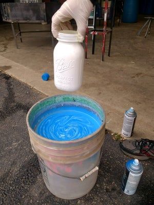 a man standing next to a bucket filled with blue liquid