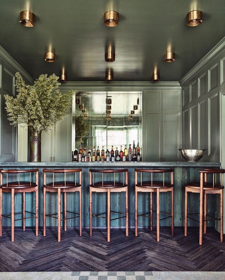 a bar with several stools and bottles on the back wall, along with two vases filled with flowers