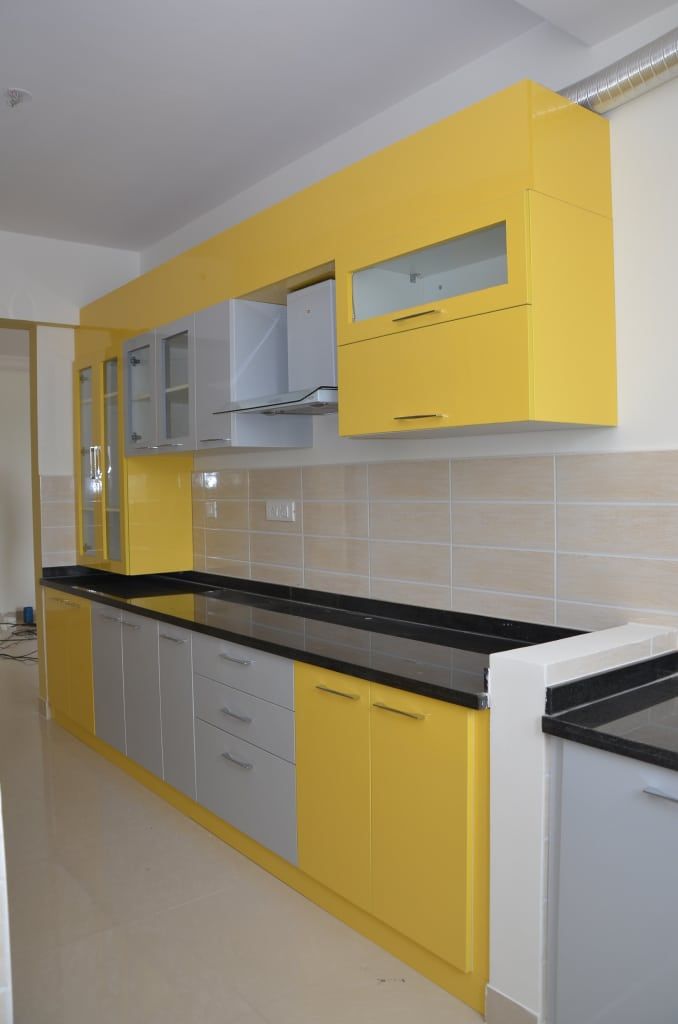 a kitchen with yellow cabinets and black counter tops