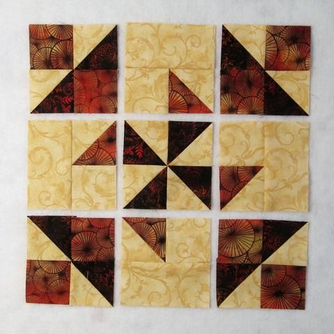 nine quilt blocks are arranged in the shape of an origami star, with red and yellow designs on them