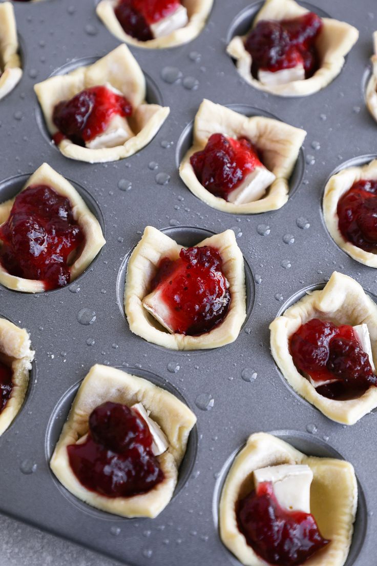 mini pastries with jelly filling in them sitting on a baking tray ready to go into the oven