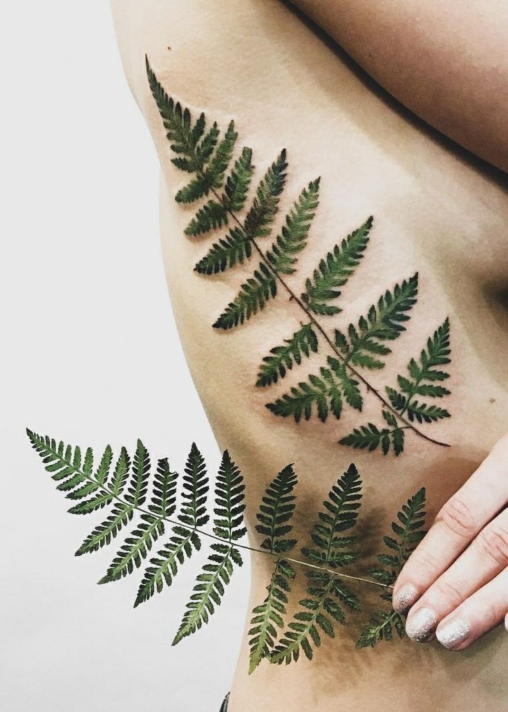 a woman's stomach with green leaves on it