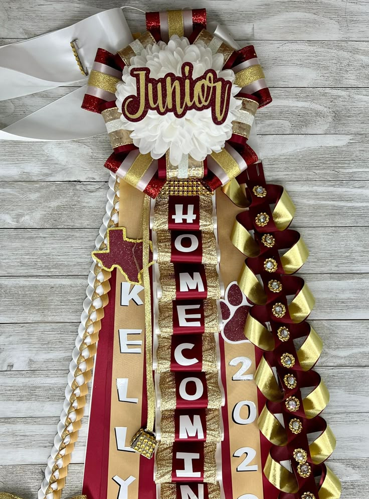 a ribbon with the word junior on it is hanging from a wooden wall next to some gold and red ribbons