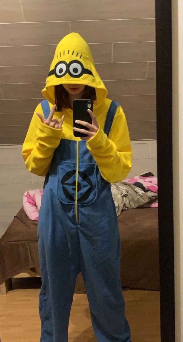 a person in a yellow jacket and blue overalls taking a selfie