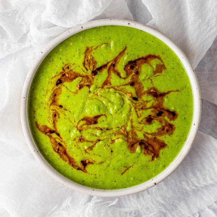 a white bowl filled with green soup on top of a table