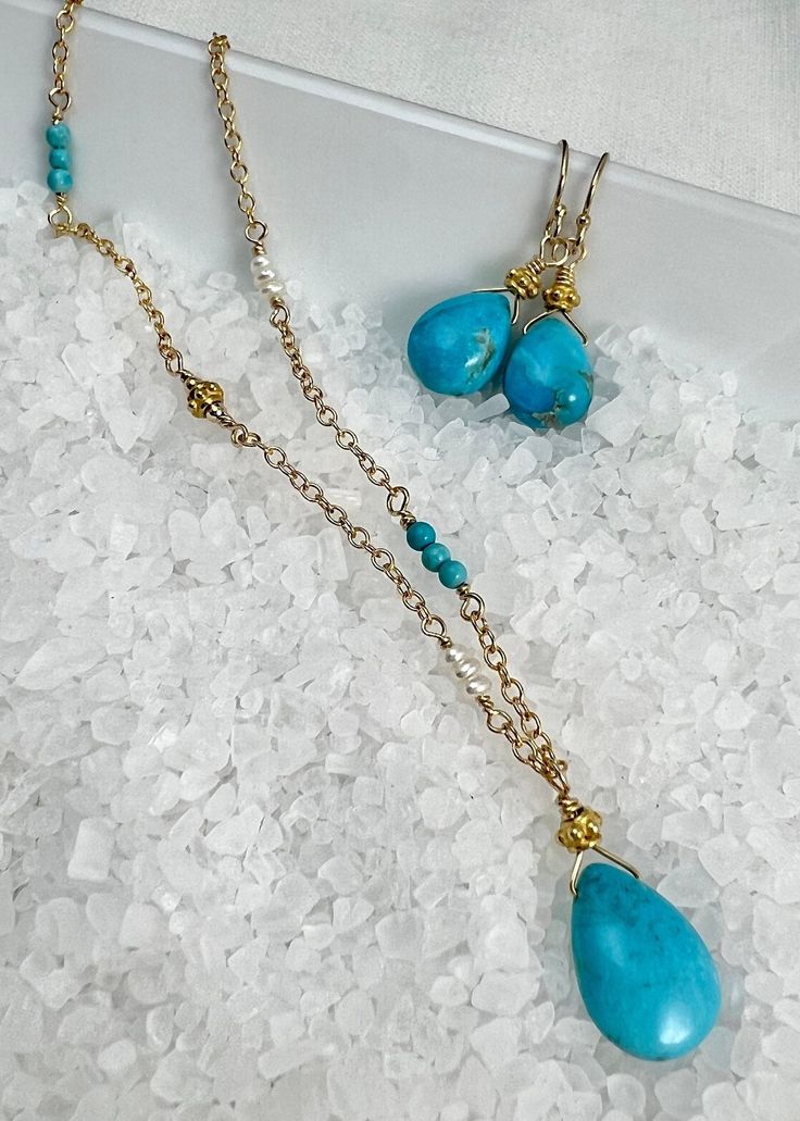 This beautiful necklace is designed with a 10mm X 15mm smooth nugget of Sleeping Beauty Turquoise (that beautiful bright blue color) and wired into a pendant with a Vermeil Bali gold bead. The pendant dangles from sparkly cable chain. Sections of the necklace are accented with tiny (2mm) smooth, round turquoise, Vermeil Bali beads that match the pendant, and tiny (2mm) white freshwater pearls for a unique one of a kind design.The look of Turquoise with gold is a beautiful change to the tradition Blue Gemstone Beads Teardrop Pendant Jewelry, Blue Teardrop Pendant With Gemstone Beads, Turquoise Teardrop Wire Wrapped Jewelry, Gold Jewelry With Gemstone Beads Teardrop Pendant, Handmade Turquoise Briolette Jewelry, Elegant Turquoise Wire Wrapped Necklace, Dangling Beads Teardrop Pendant Jewelry For Gift, Teardrop Pendant Jewelry With Dangling Beads For Gift, Elegant Wire Wrapped Turquoise Necklace Gift