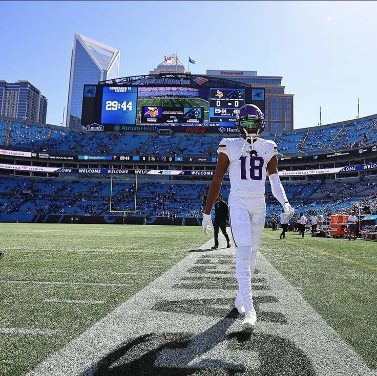 a football player walking on the field in front of an empty stadium filled with people