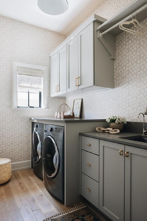 a washer and dryer in a room with white walls, wooden floors and cabinets