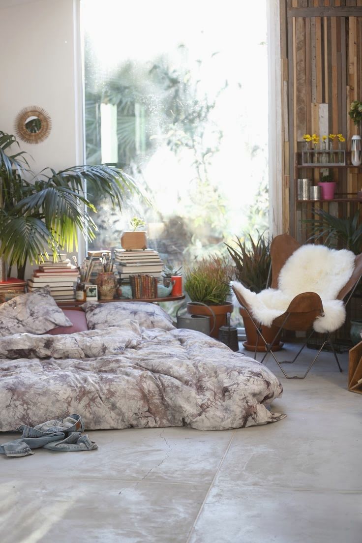 a bed sitting in the middle of a living room next to a plant filled wall