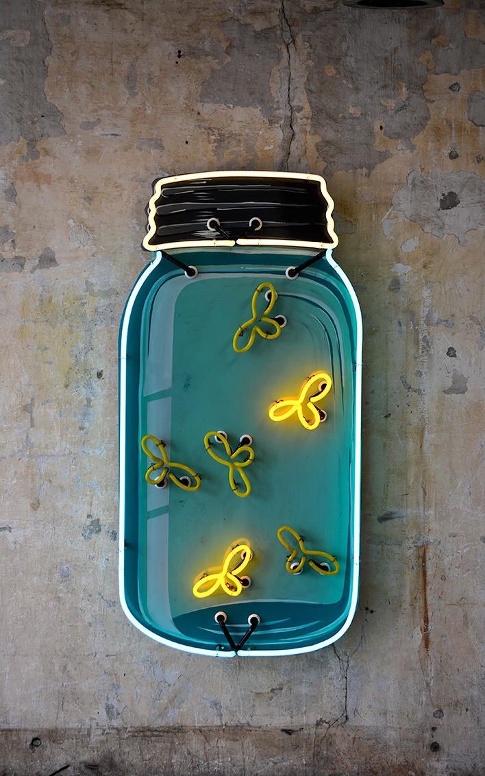 a mason jar with neon yellow butterflies in it hanging on the side of a wall