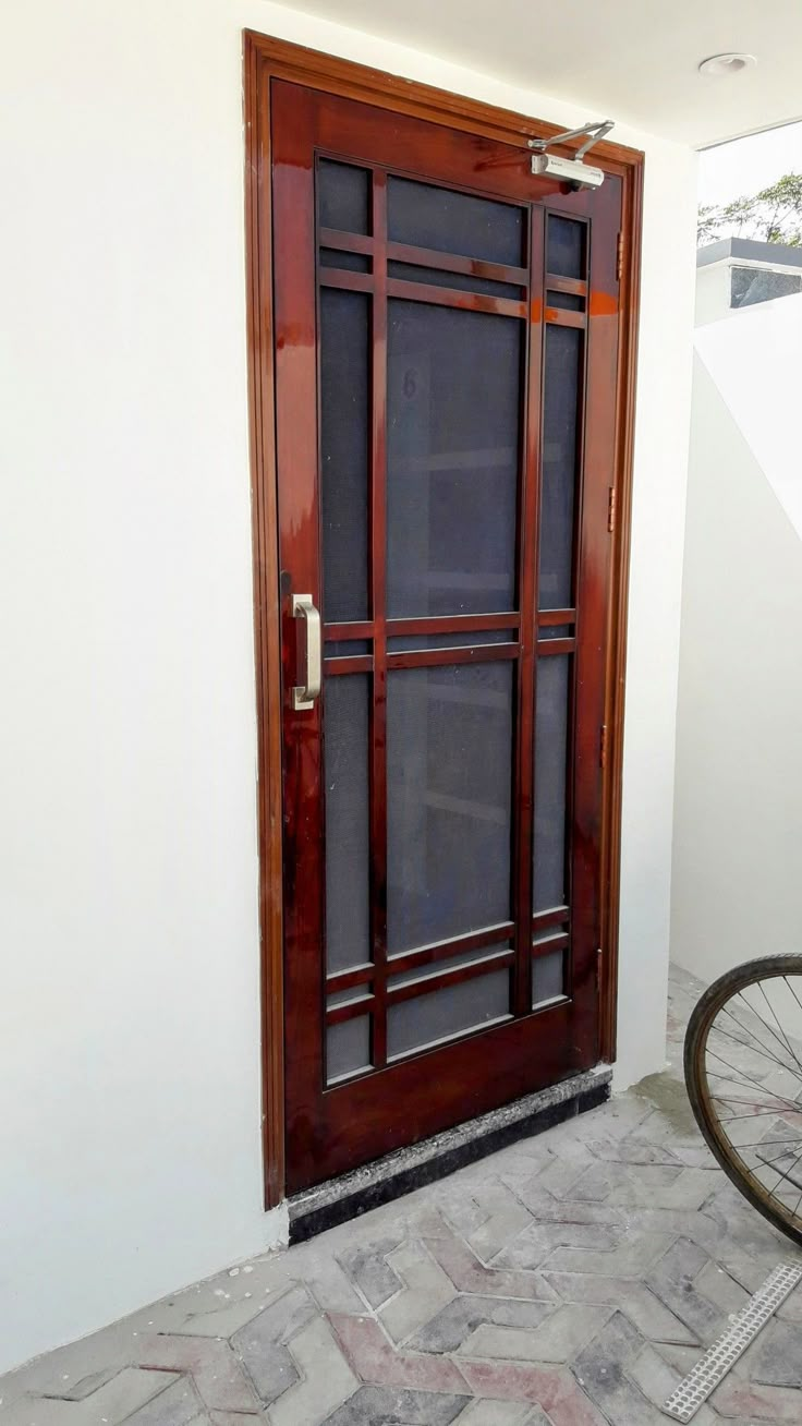 a bicycle parked in front of a wooden door with glass panels on the outside wall