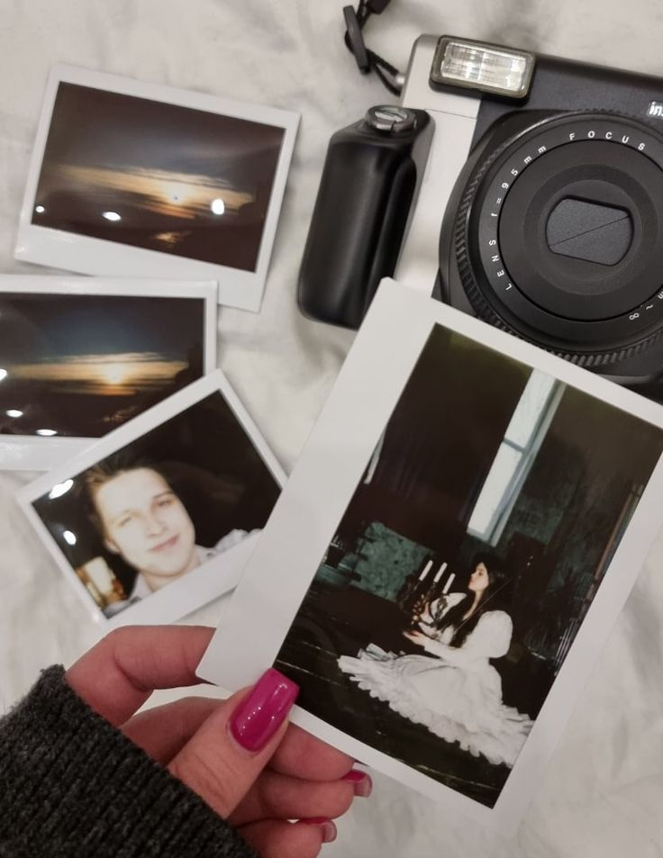 a person holding up an old photo next to other polaroid pictures and a camera