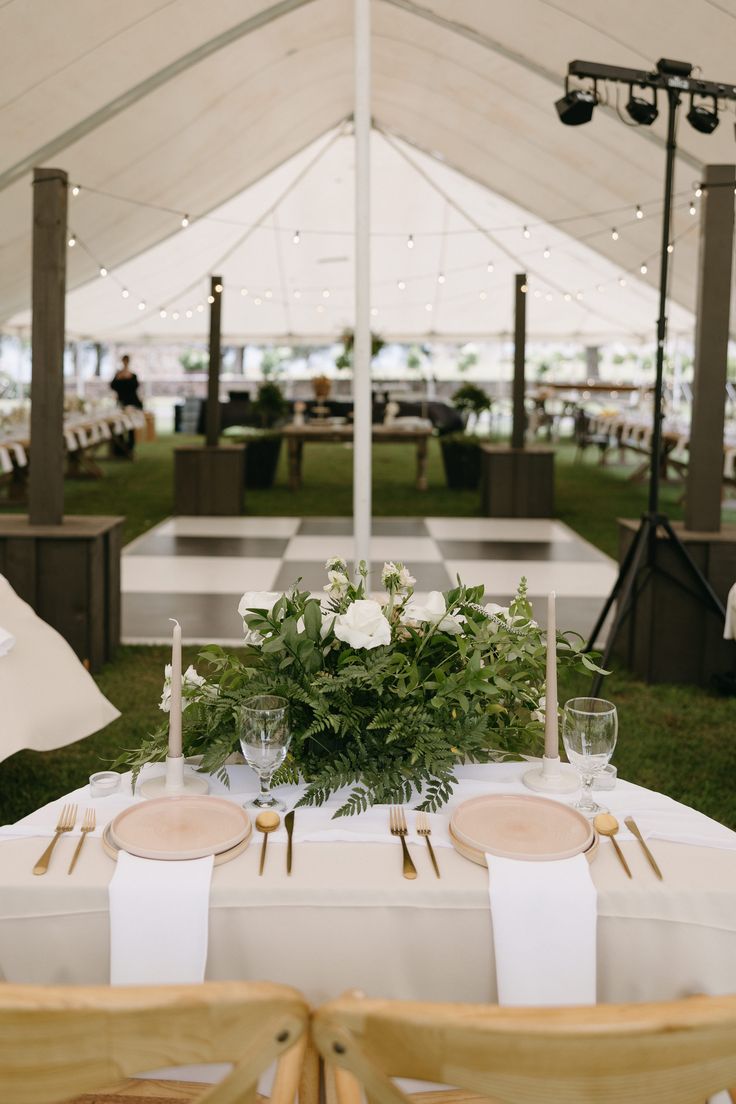 a table set up with place settings and flowers on it for an outdoor wedding reception