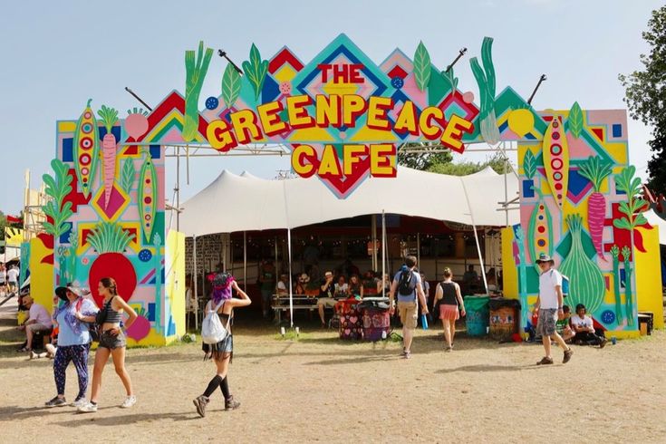 people are walking in front of the greenpeace stage at an amusement park,