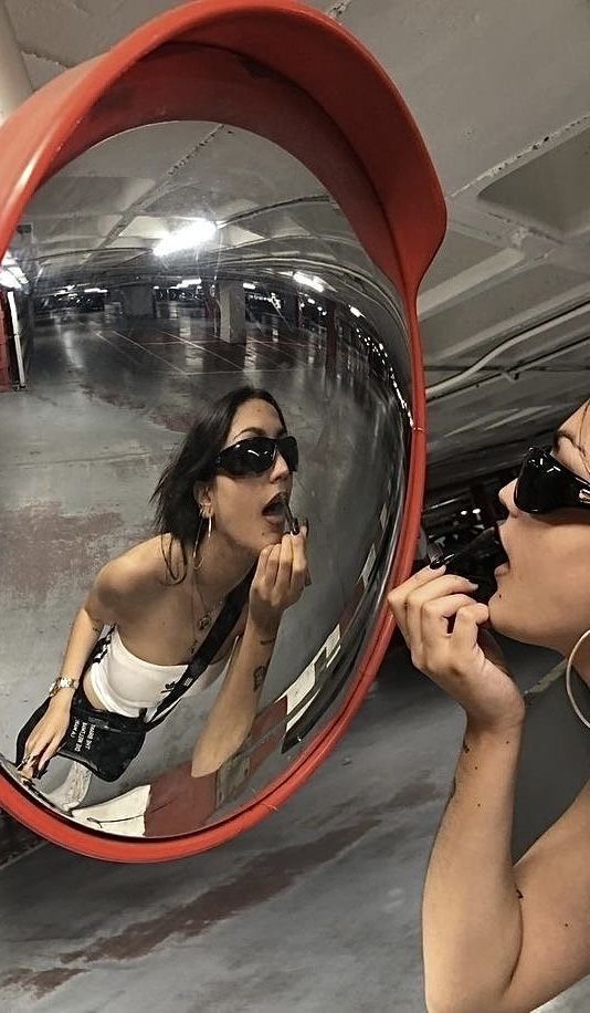 a woman is brushing her teeth in front of a large round mirror with red trim