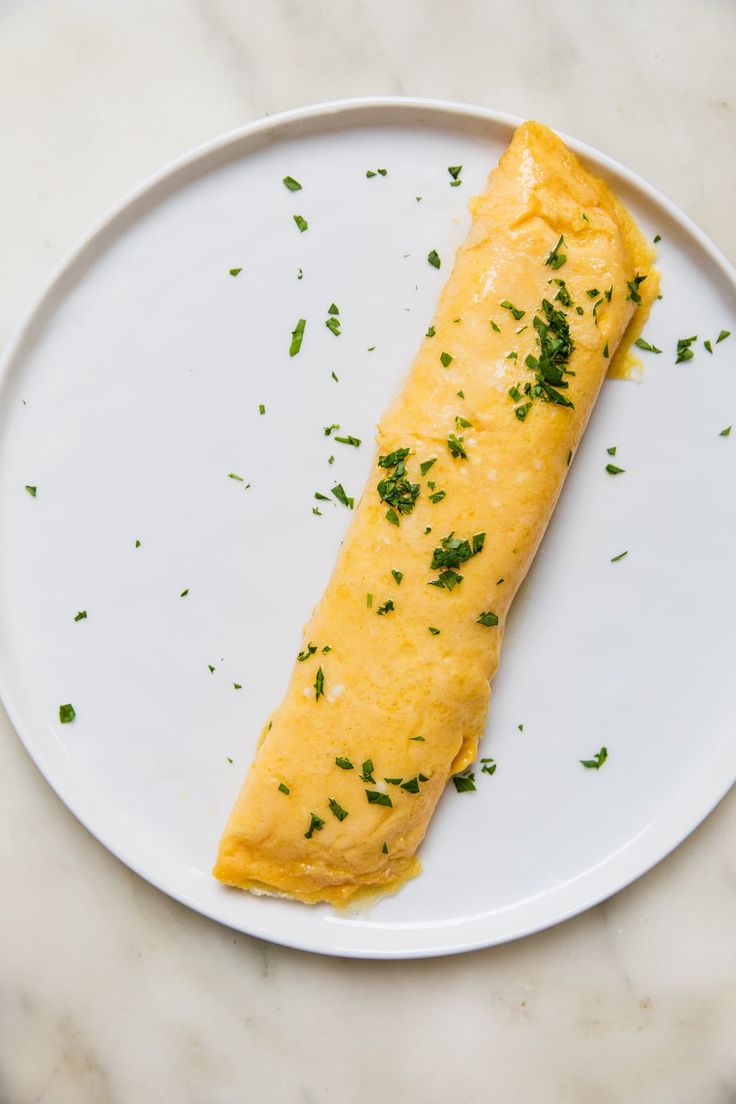 an omelet on a plate with parsley sprinkled on it's side