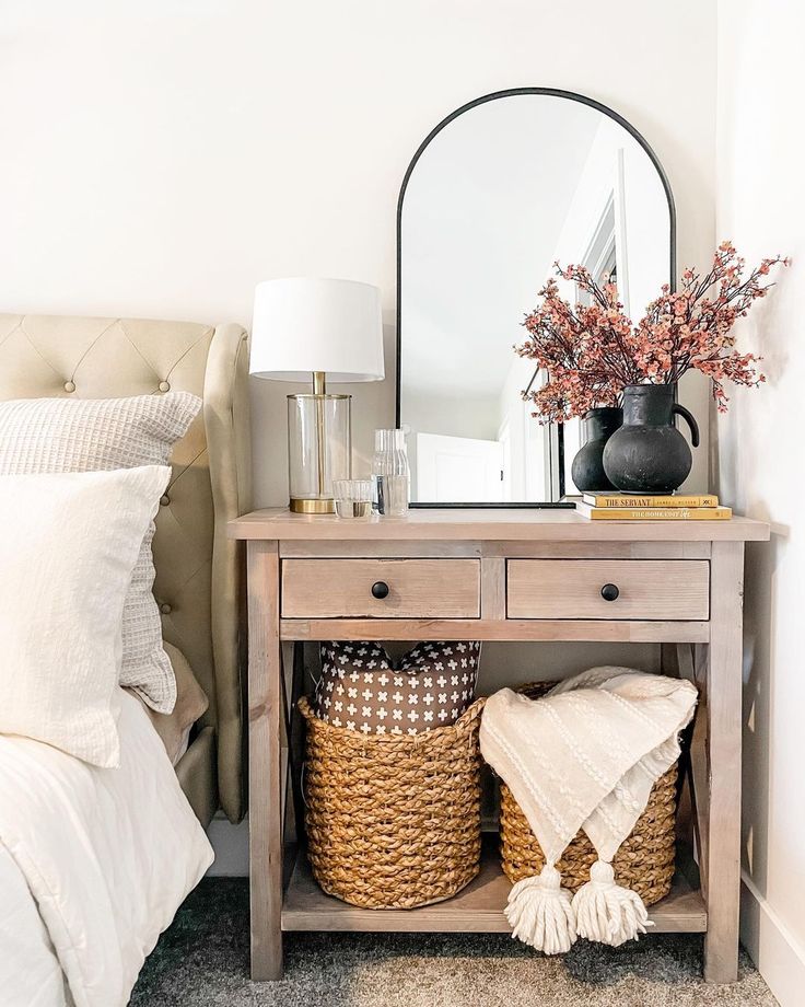 a bedroom with a bed, mirror and two wicker baskets on the side table