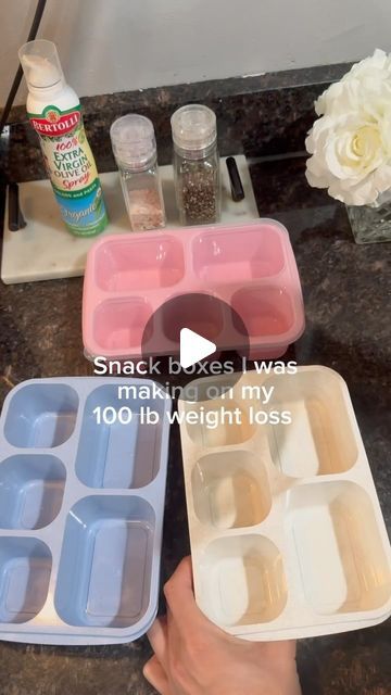 someone is holding two plastic containers with food in them on a counter top next to flowers