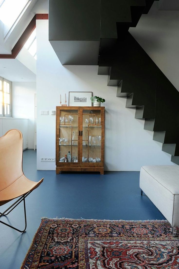 a living room with blue floors and a stair case next to a white couch on top of a rug