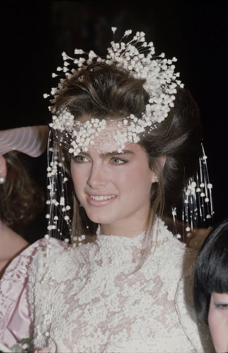 a woman wearing a white dress and headpiece with flowers on it's hair