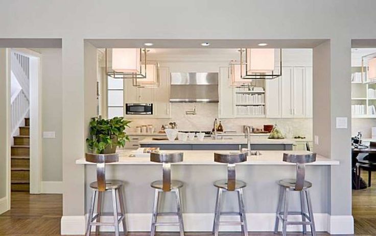 an open concept kitchen with white cabinets and stainless steel bar stools in the center